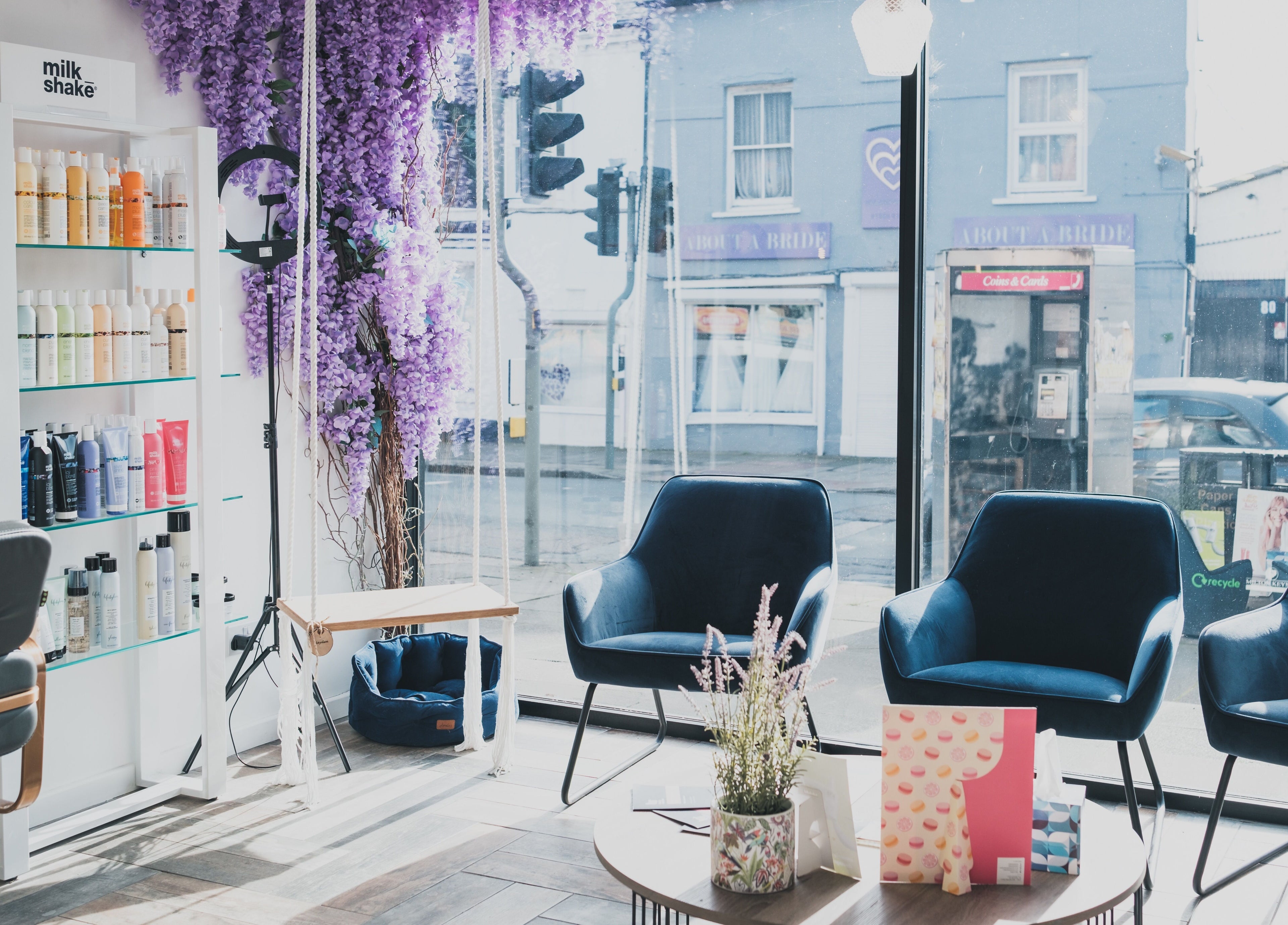 Elegant seating area at Hayden Hair Studio, Bletchley, England, GB showcasing purple decor and product display.
