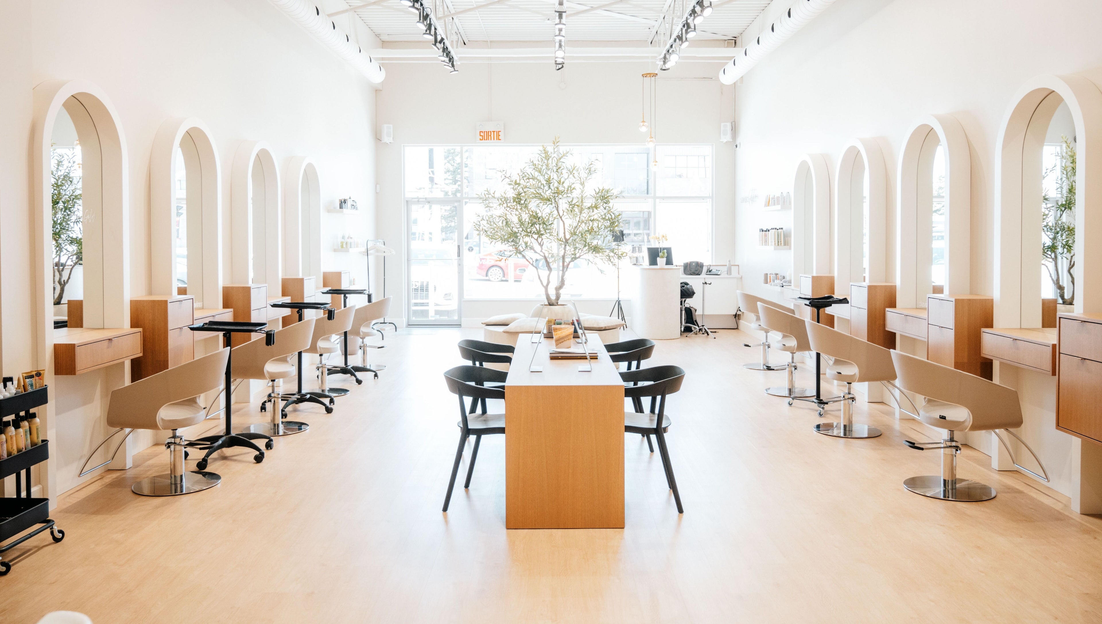 Modern interior of Salon Goldn in Laval, Québec, CA with chic styling stations and natural lighting.