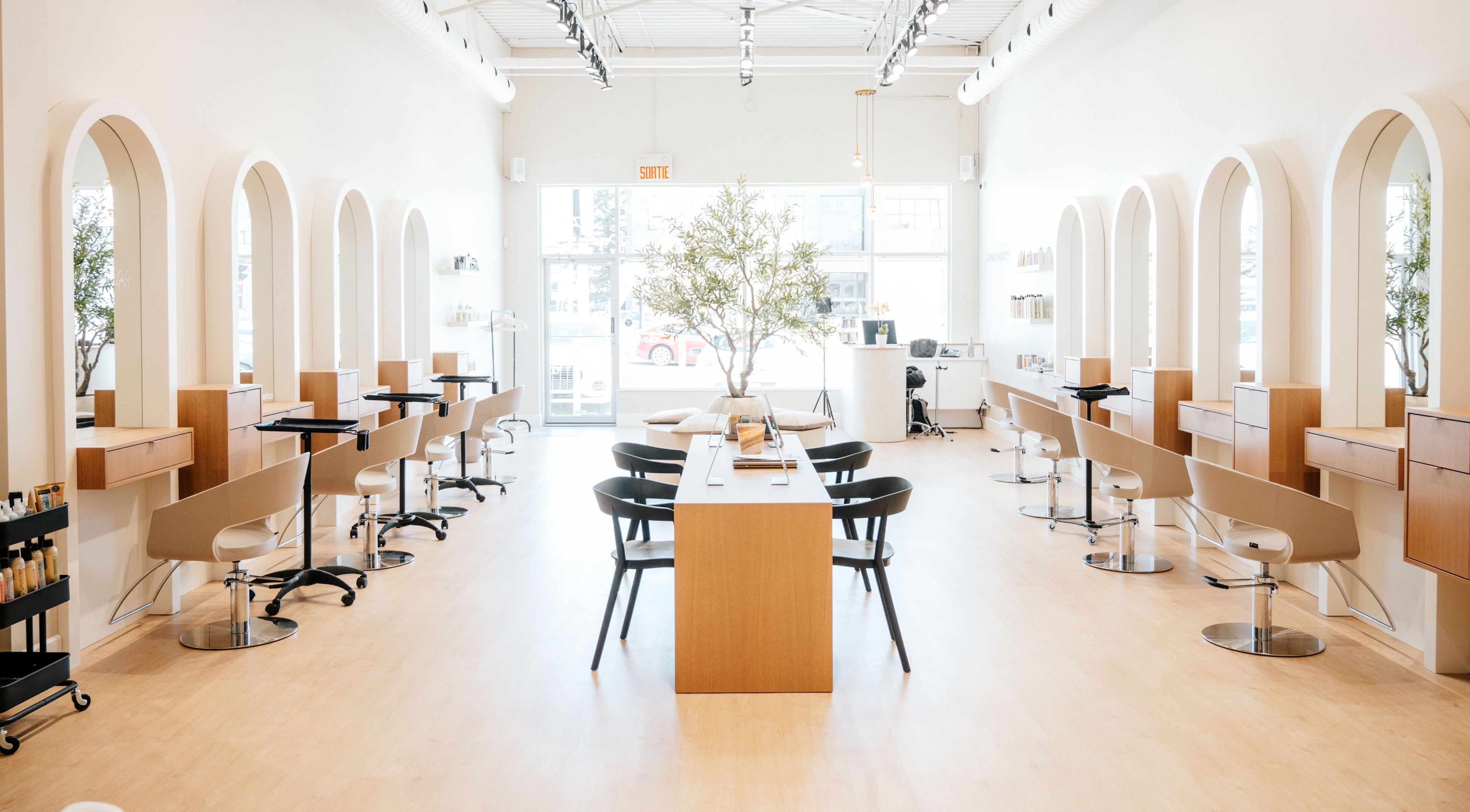 Modern interior of Salon Goldn in Laval, Québec, CA with chic styling stations and natural lighting.