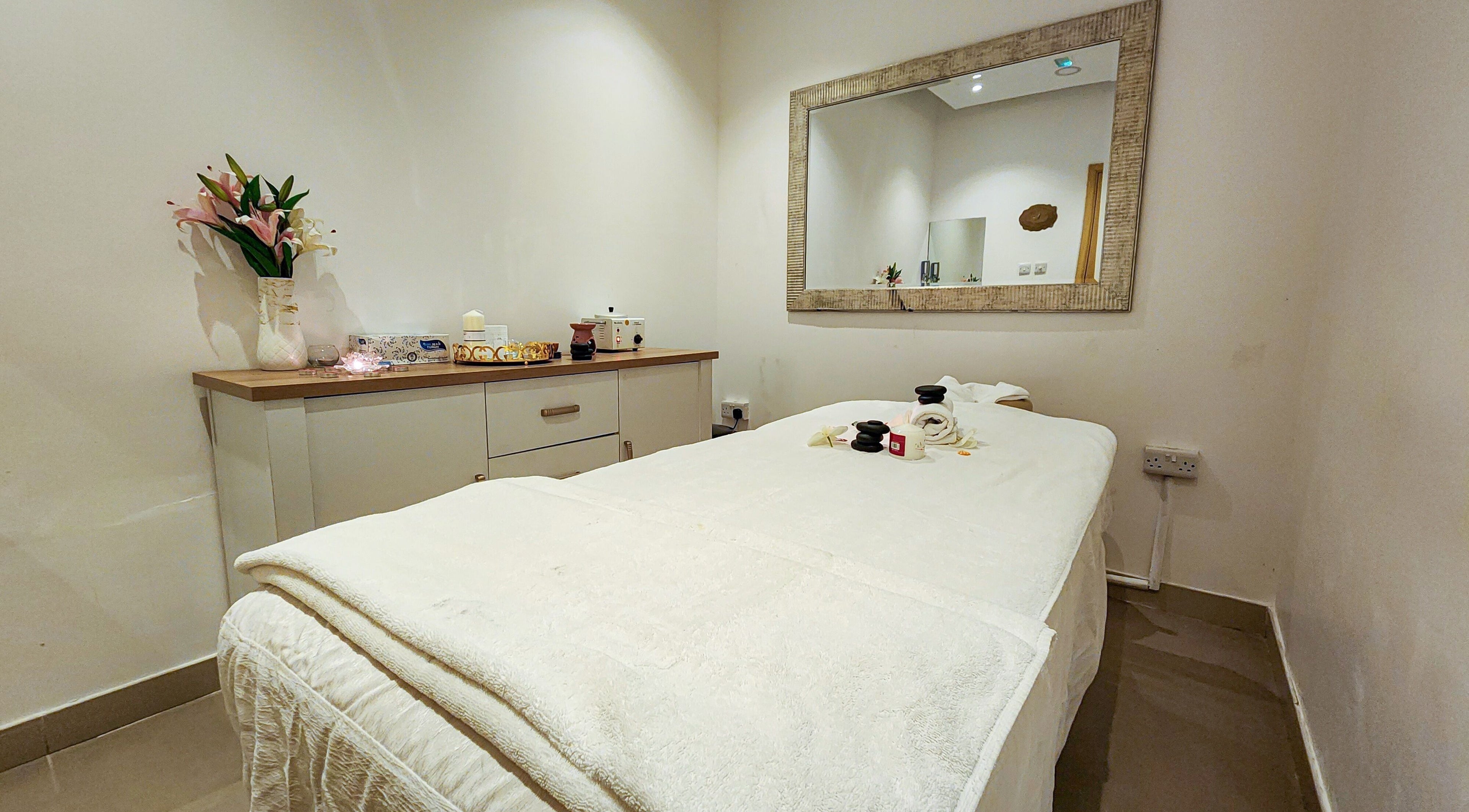 Relaxing spa room at Cut and Colours Beauty Center, Abu Dhabi, AE, featuring a massage table and calming decor.