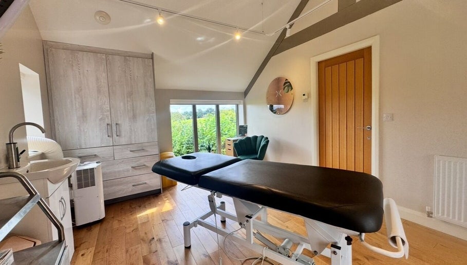 Modern treatment room at KK Clinic, Ashby-de-la-zouch, England, GB with a massage table and natural light.