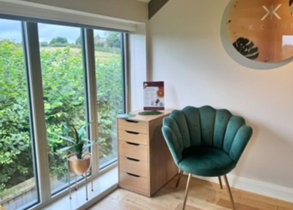 Elegant waiting area of KK Clinic with a green chair and large window in Ashby-de-la-Zouch, England, GB.