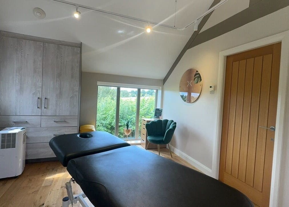 KK Clinic treatment room in Ashby-de-la-Zouch, England, featuring a massage table and green chair.