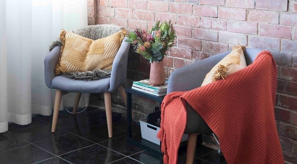 Inviting seating area at Tuca Salon, Melbourne, Victoria, AU, with comfy chairs and soft throws.