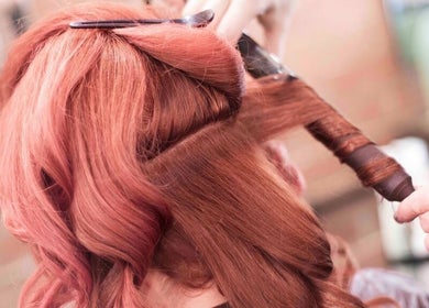 Stylist expertly curling red hair at Tuca Salon in Melbourne, Victoria, AU for a perfect hairstyle finish.