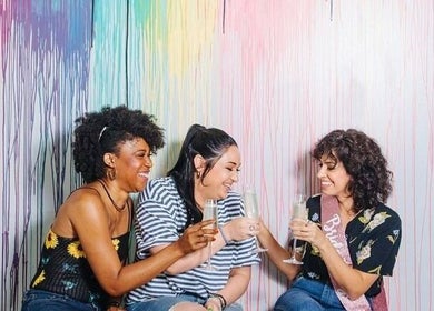 Friends celebrating at Color Me True Nail Bar, Nashville, Tennessee, US with colorful wall backdrop.