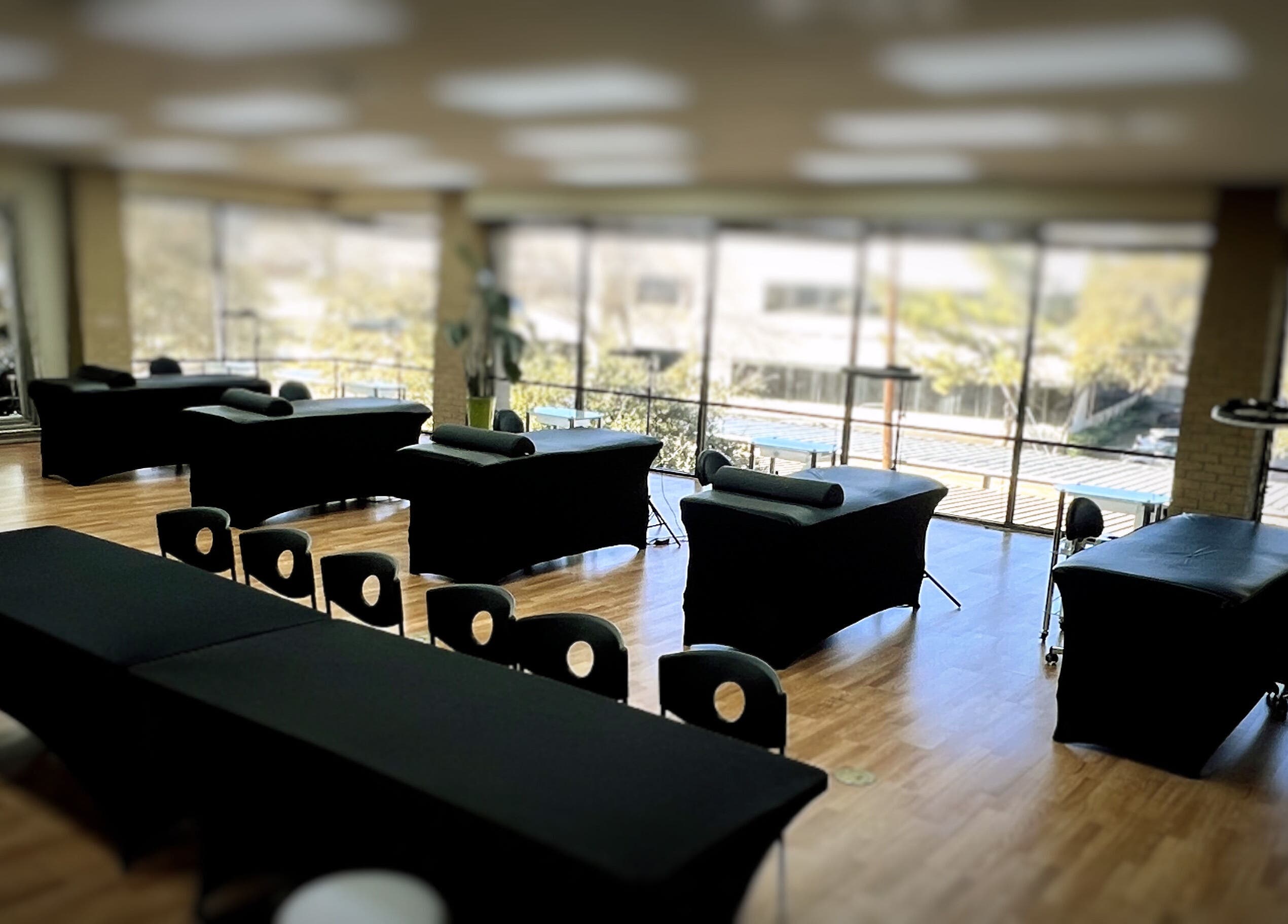 Spacious, sunlit interior of 5 Star Academy, Dallas, Texas, US with massage tables and large windows.
