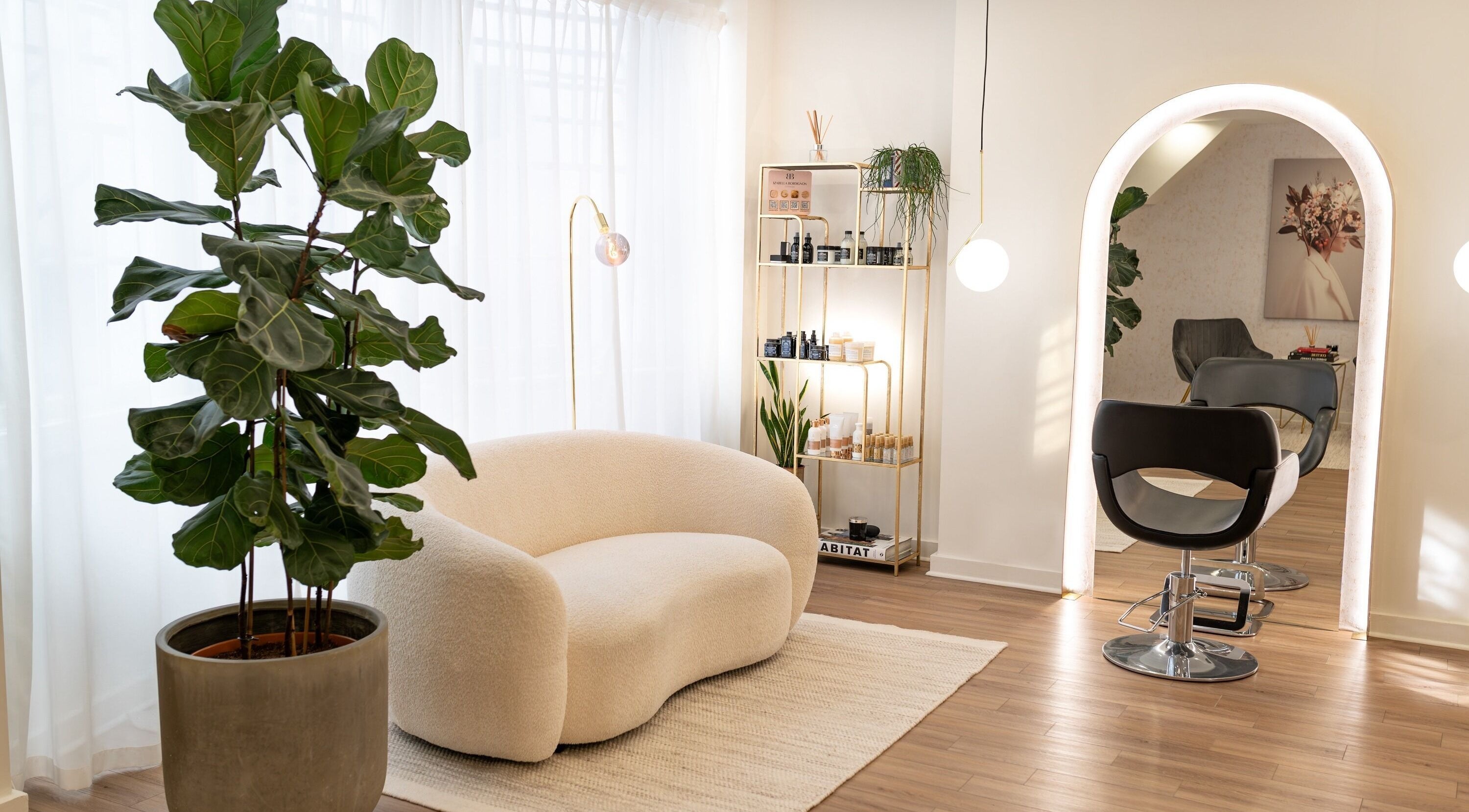 Modern salon interior at Izabella Bordignon - Hair Boutique, London, England, GB featuring cozy seating and lush plants.
