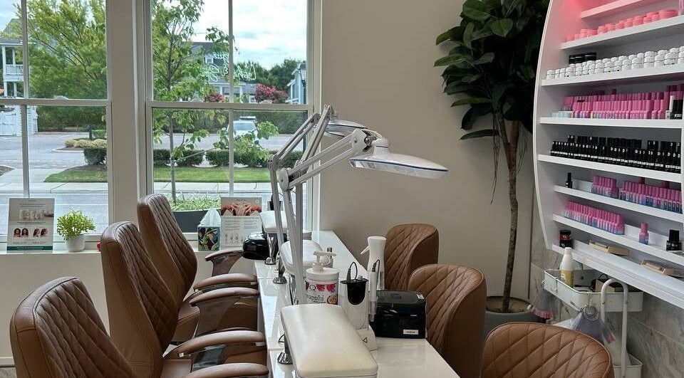 Modern nail station at At East Beach - Vogue Lashes & Spa in Norfolk, Virginia, US with lush greenery outside.