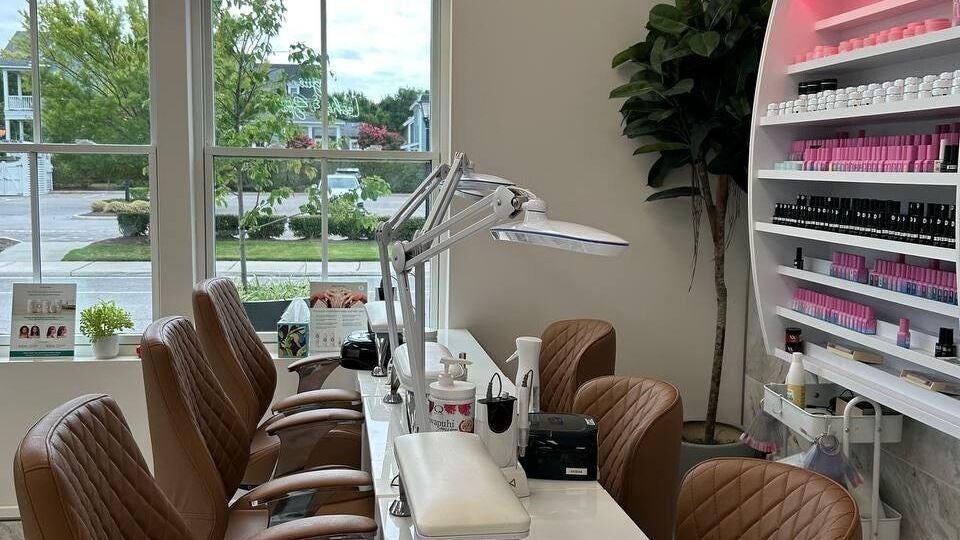 Modern nail station at At East Beach - Vogue Lashes & Spa in Norfolk, Virginia, US with lush greenery outside.