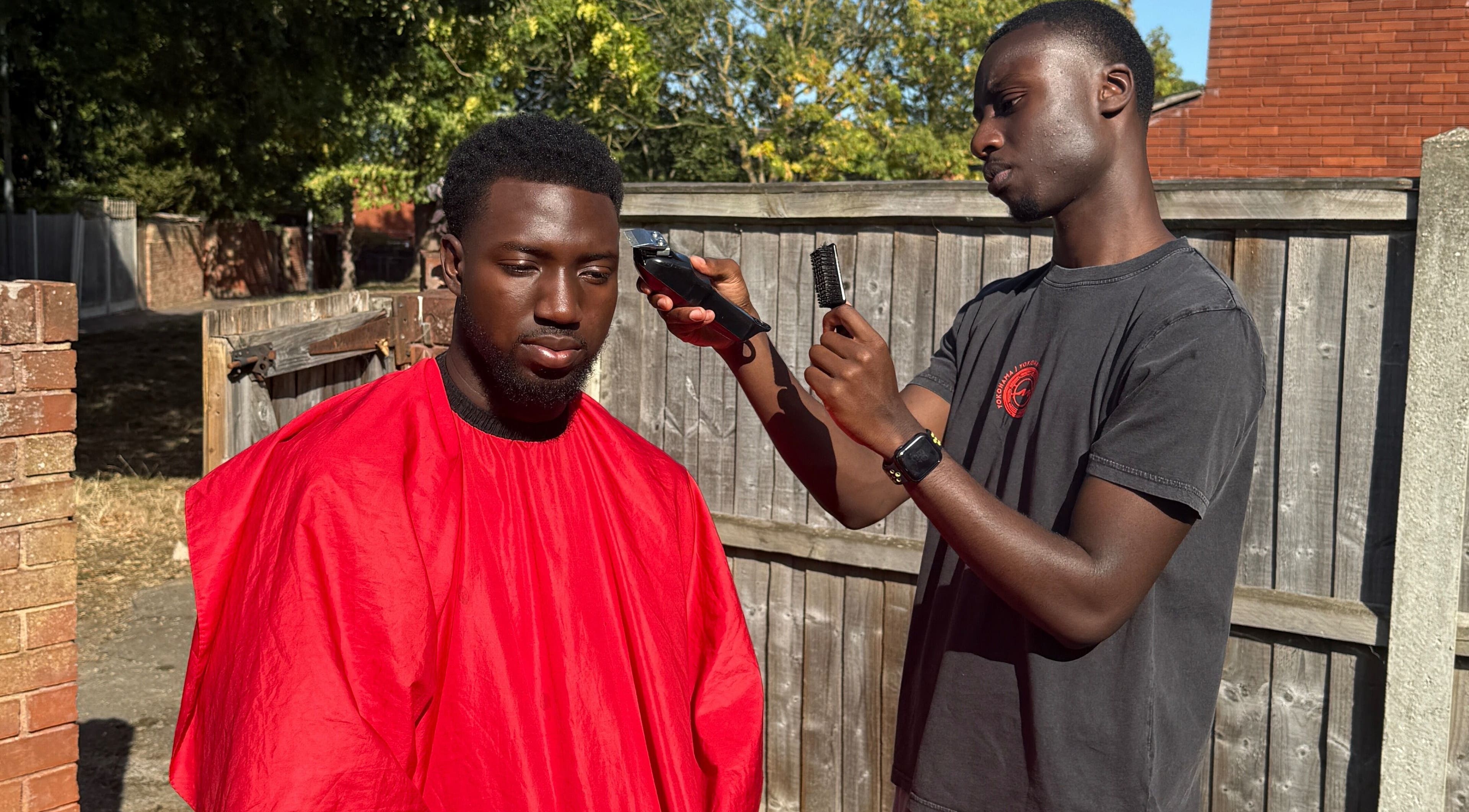 Barber giving haircut outdoors at AB Fadez, Nottingham, England, GB.