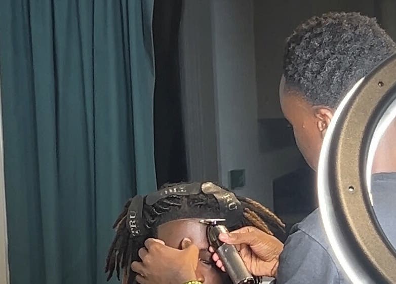 Professional stylist at AB Fadez, Nottingham, England, GB trimming hair with precision.