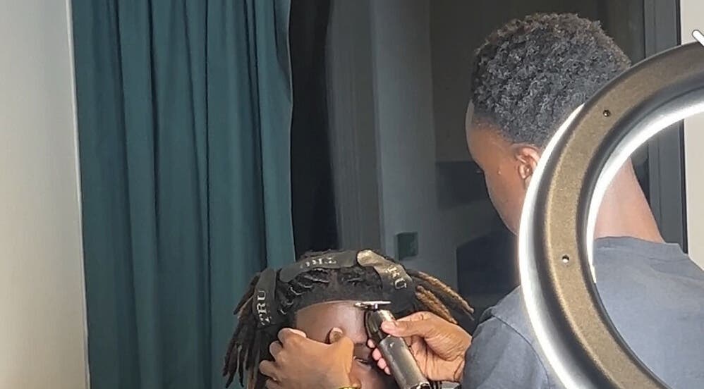 Professional stylist at AB Fadez, Nottingham, England, GB trimming hair with precision.