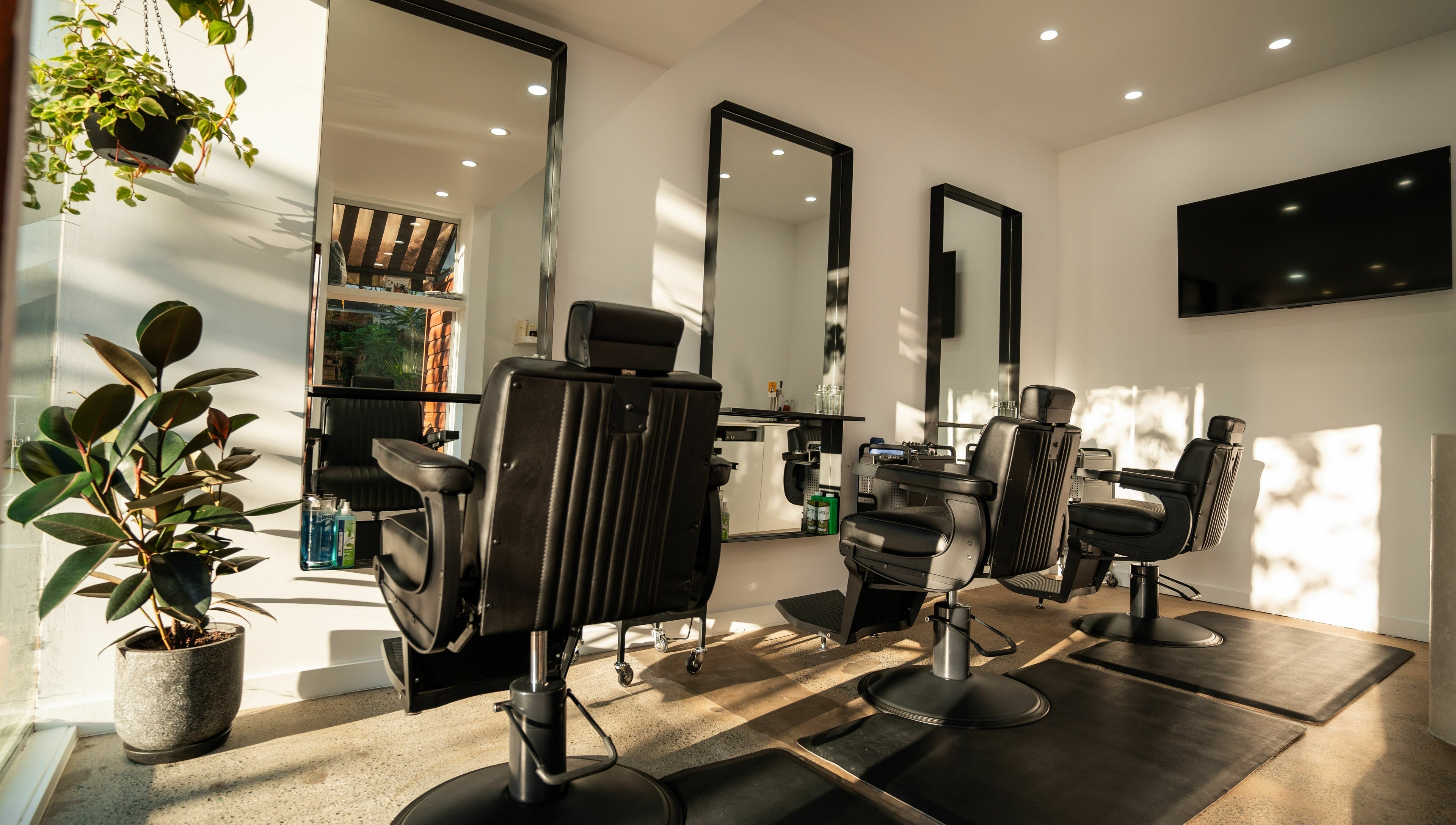 Interior of Lost Boys Burleigh salon in Burleigh Heads, Queensland, AU with modern chairs and greenery.