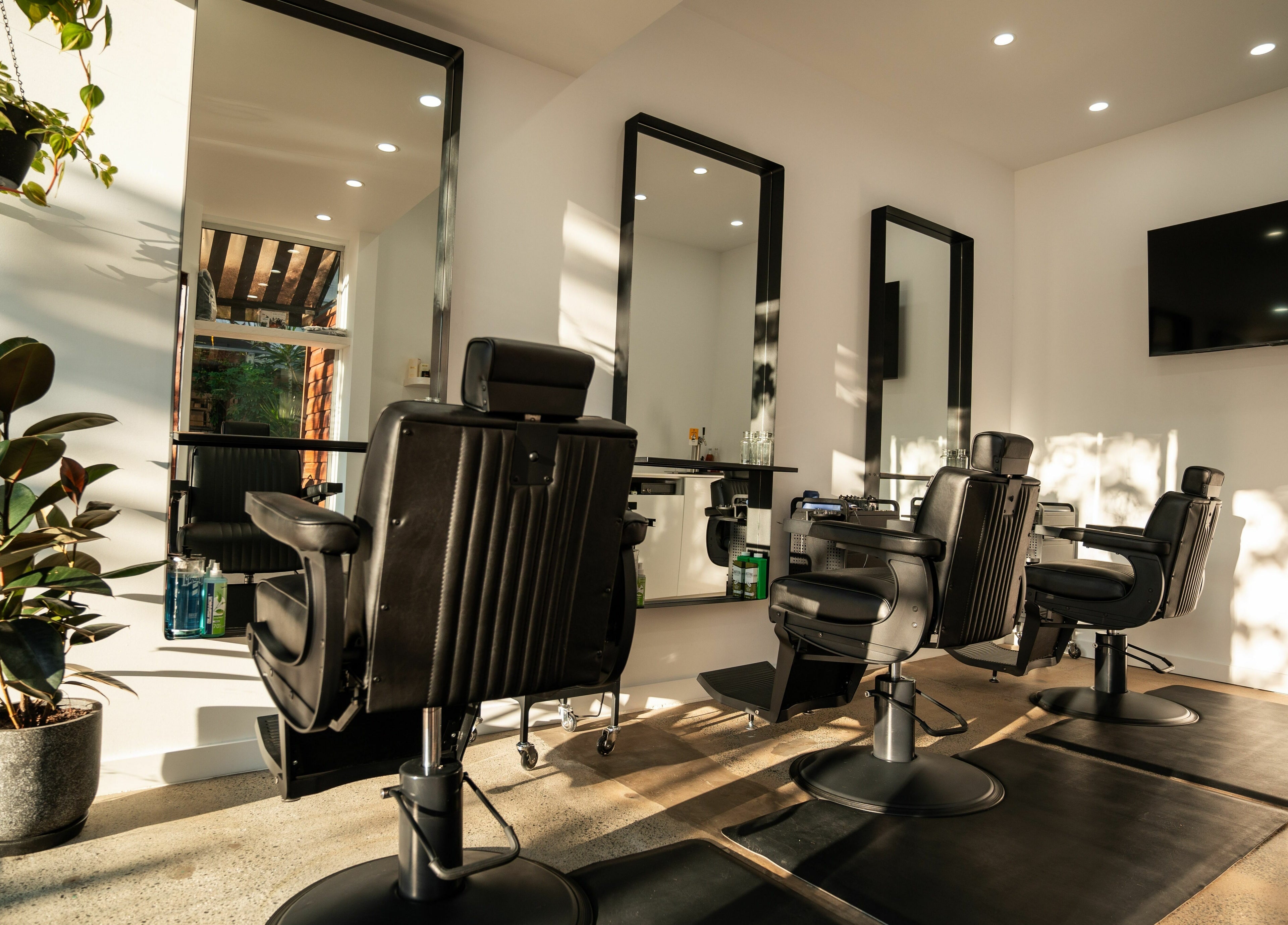 Interior of Lost Boys Burleigh salon in Burleigh Heads, Queensland, AU with modern chairs and greenery.