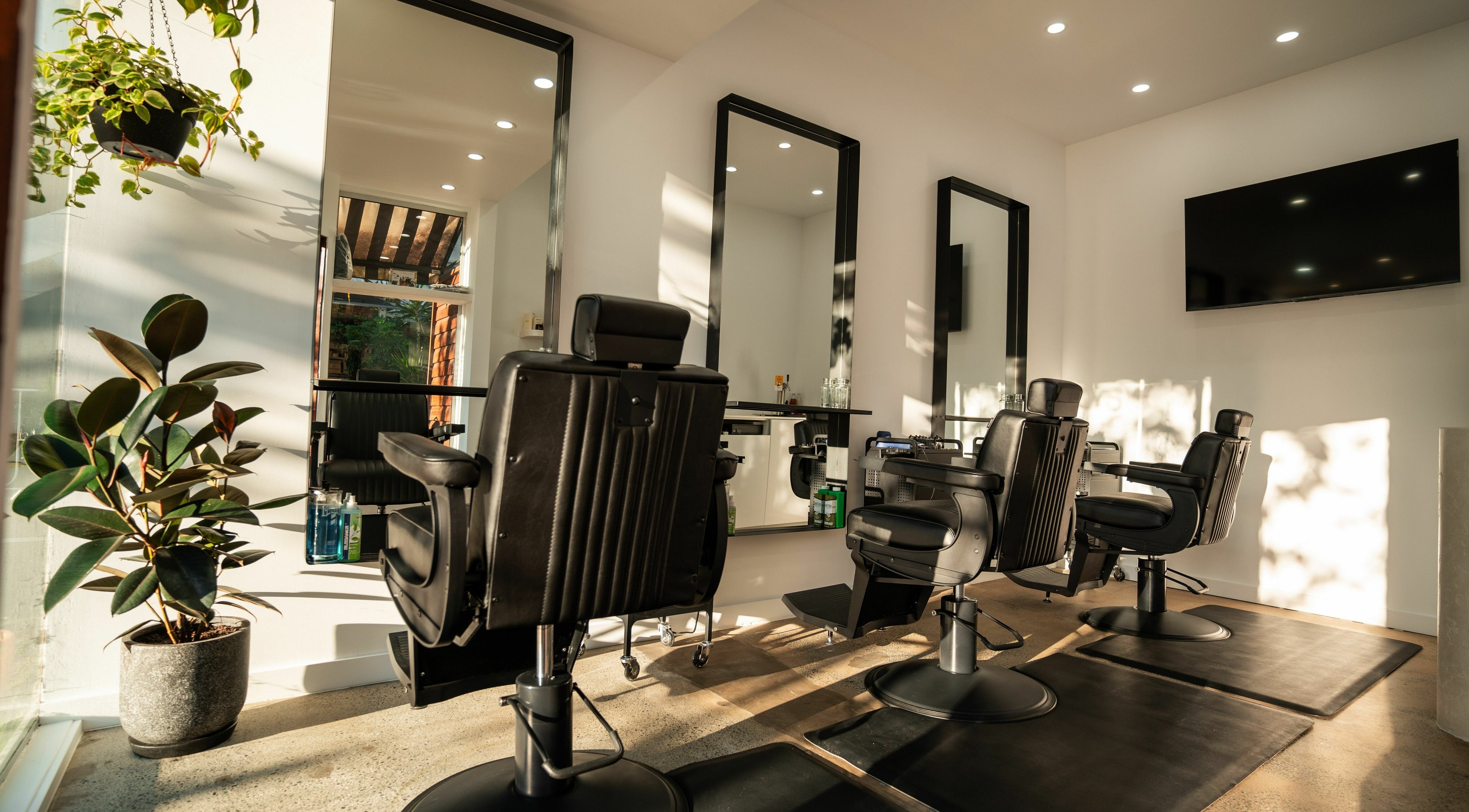 Interior of Lost Boys Burleigh salon in Burleigh Heads, Queensland, AU with modern chairs and greenery.