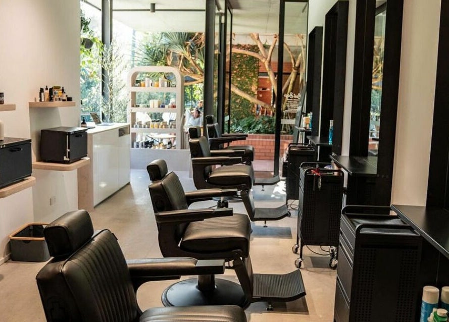 Modern salon interior at Lost Boys Burleigh, Burleigh Heads, Queensland, AU with sleek black chairs.
