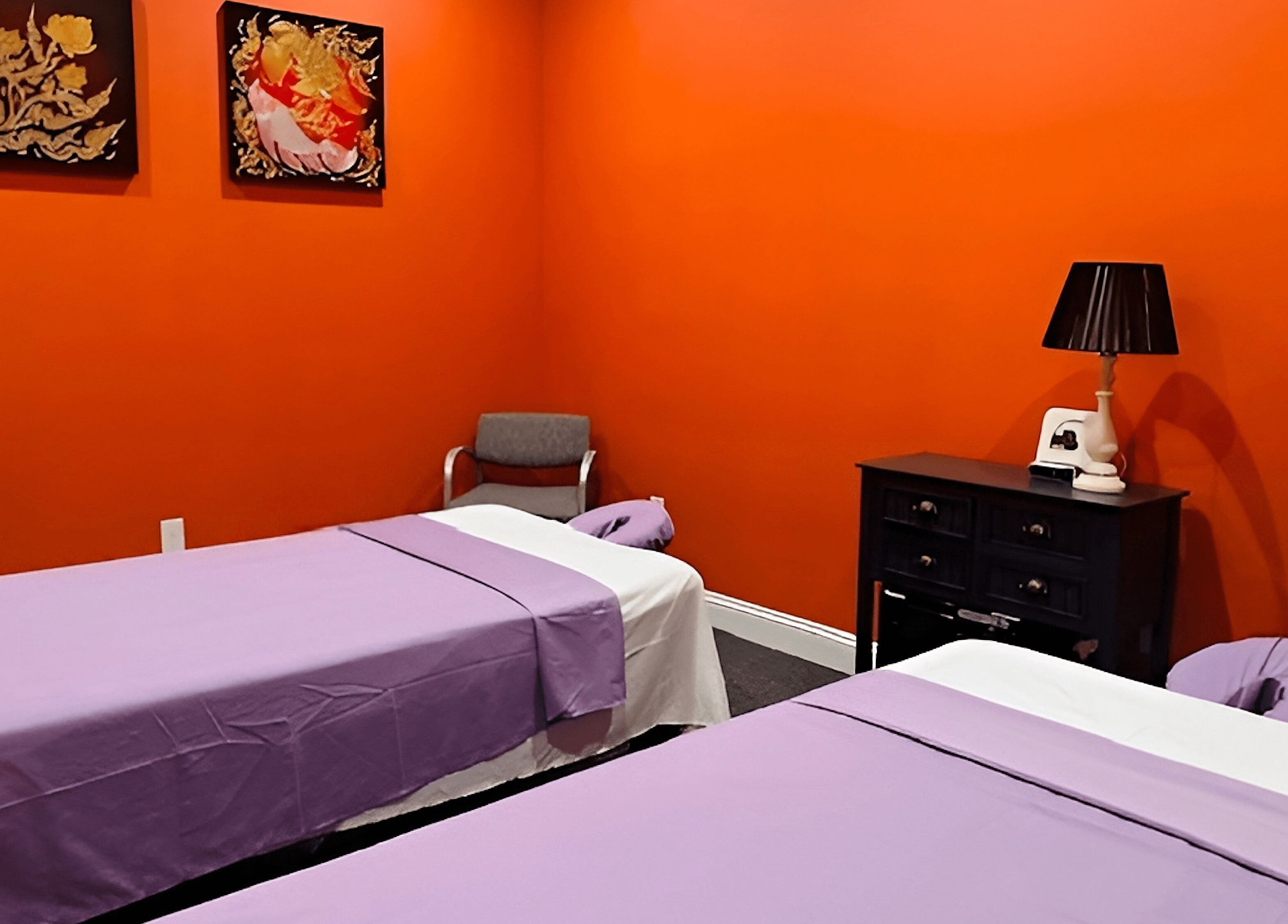 Peaceful massage room at Erawan Thai Massage at Frisco, Frisco, Texas, US, with vibrant orange walls and twin beds.