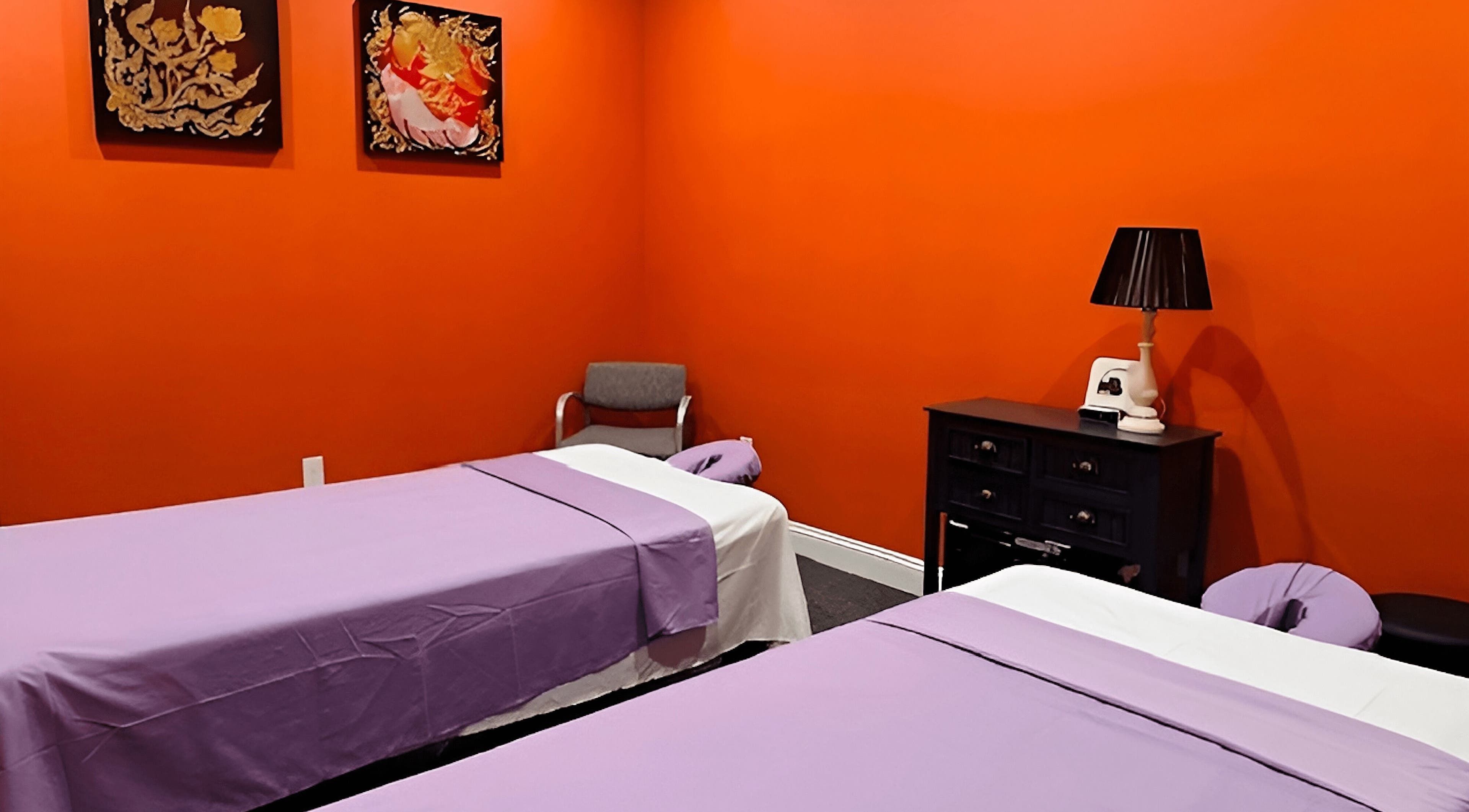 Peaceful massage room at Erawan Thai Massage at Frisco, Frisco, Texas, US, with vibrant orange walls and twin beds.