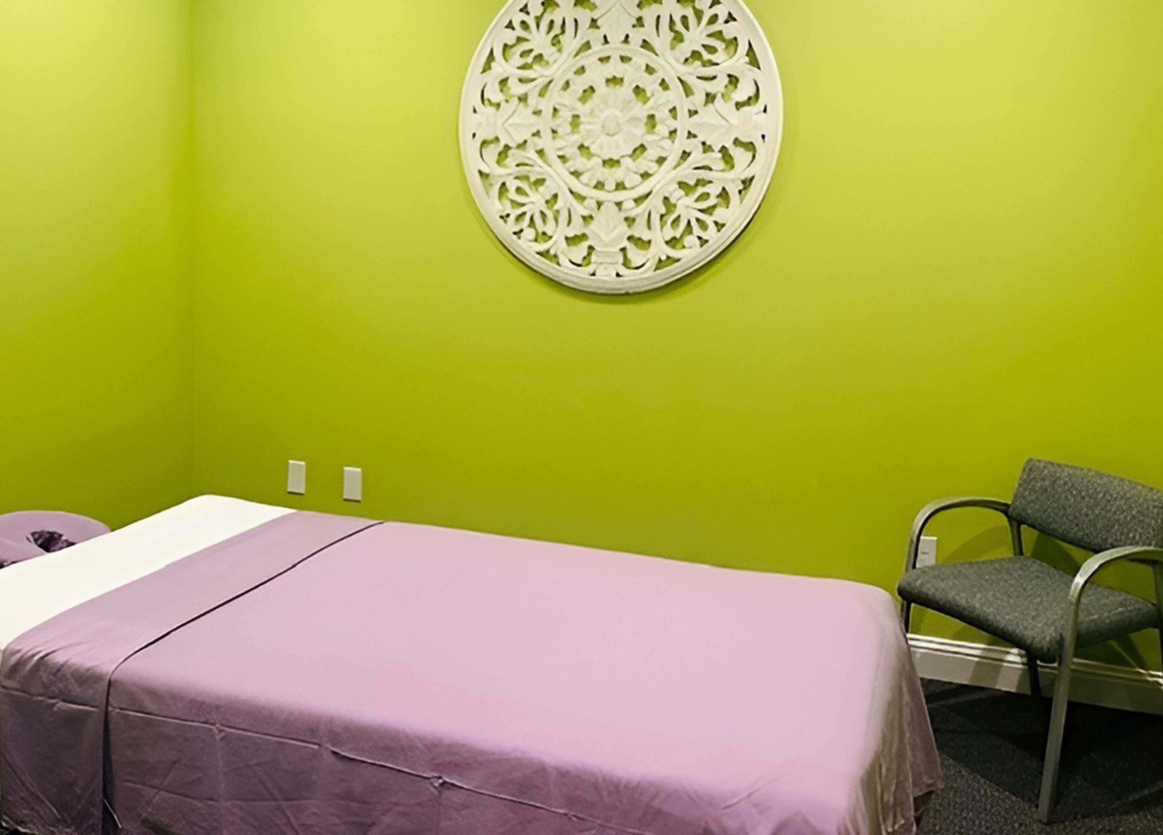 Calming massage room at Erawan Thai Massage at Frisco, Texas, US with a vibrant green wall and purple cover.