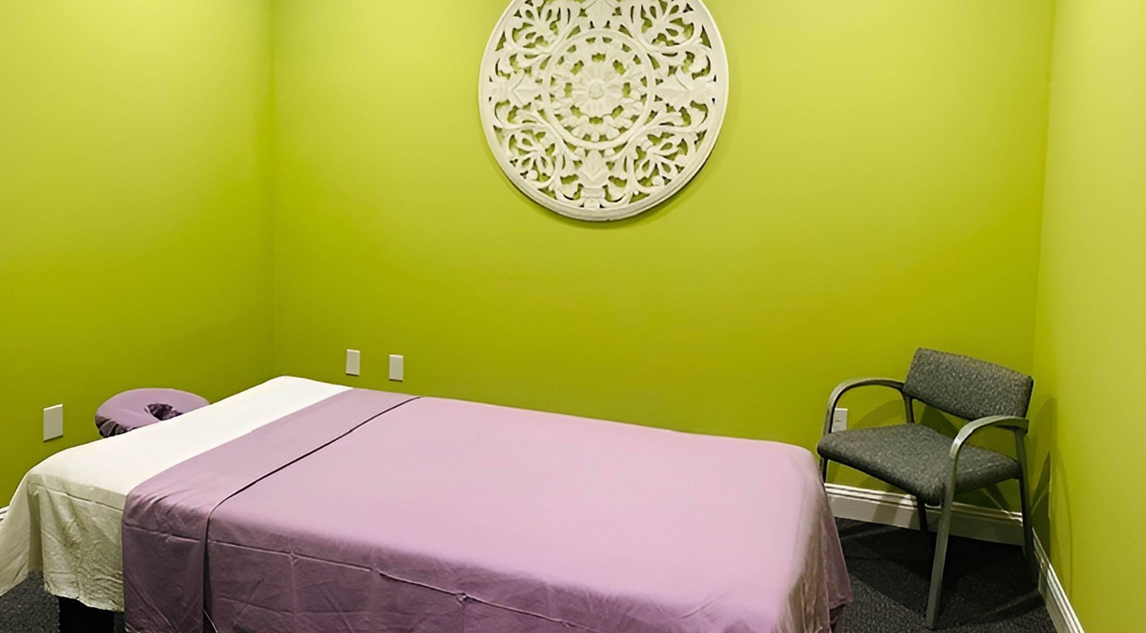 Calming massage room at Erawan Thai Massage at Frisco, Texas, US with a vibrant green wall and purple cover.