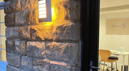 Inviting stone entrance lit at Aphrodite Lash, Worsbrough, England. A cozy ambiance welcomes visitors.