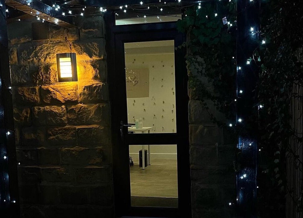 Entrance of Aphrodite Lash in Worsbrough, England, GB, lit by warm lights and fairy string lights.