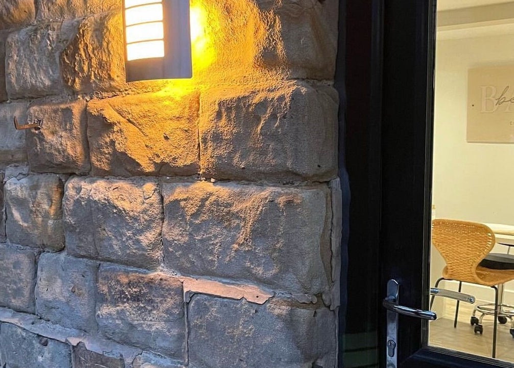 Exterior of Aphrodite Lash in Worsbrough, England, GB, with stone wall and inviting light.