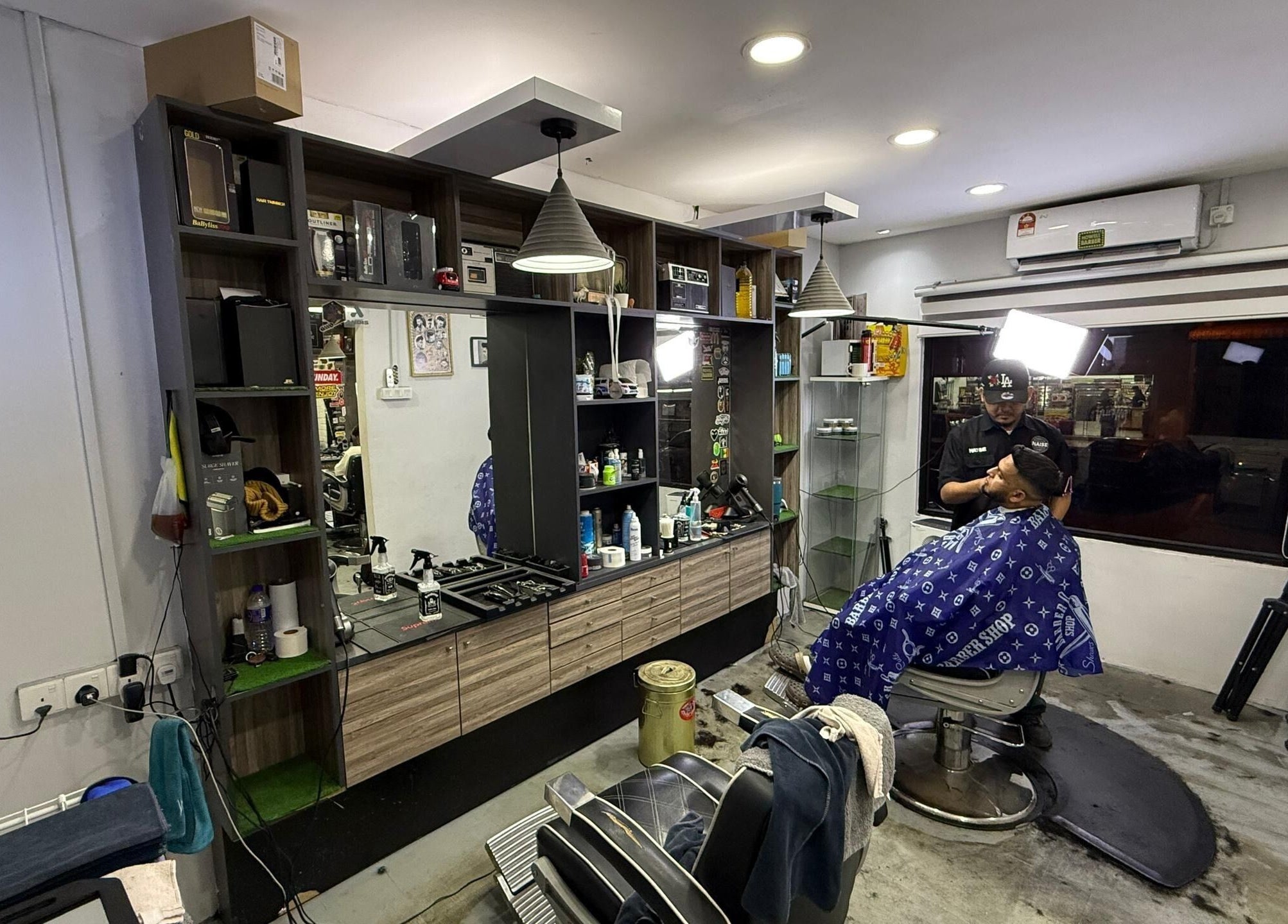Interior of Brothers Barbershop Tiram showing barber and client in Ulu Tiram, Johor, MY.