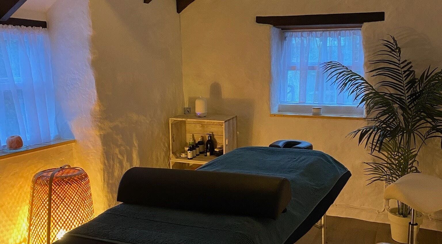 Tranquil massage room at Attes Massage in Madron, England, GB with cozy lighting and inviting decor.
