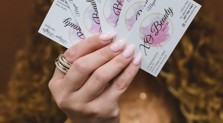 Elegantly manicured hand holding Xo Beauty cards at North Wales, Pennsylvania, US venue.