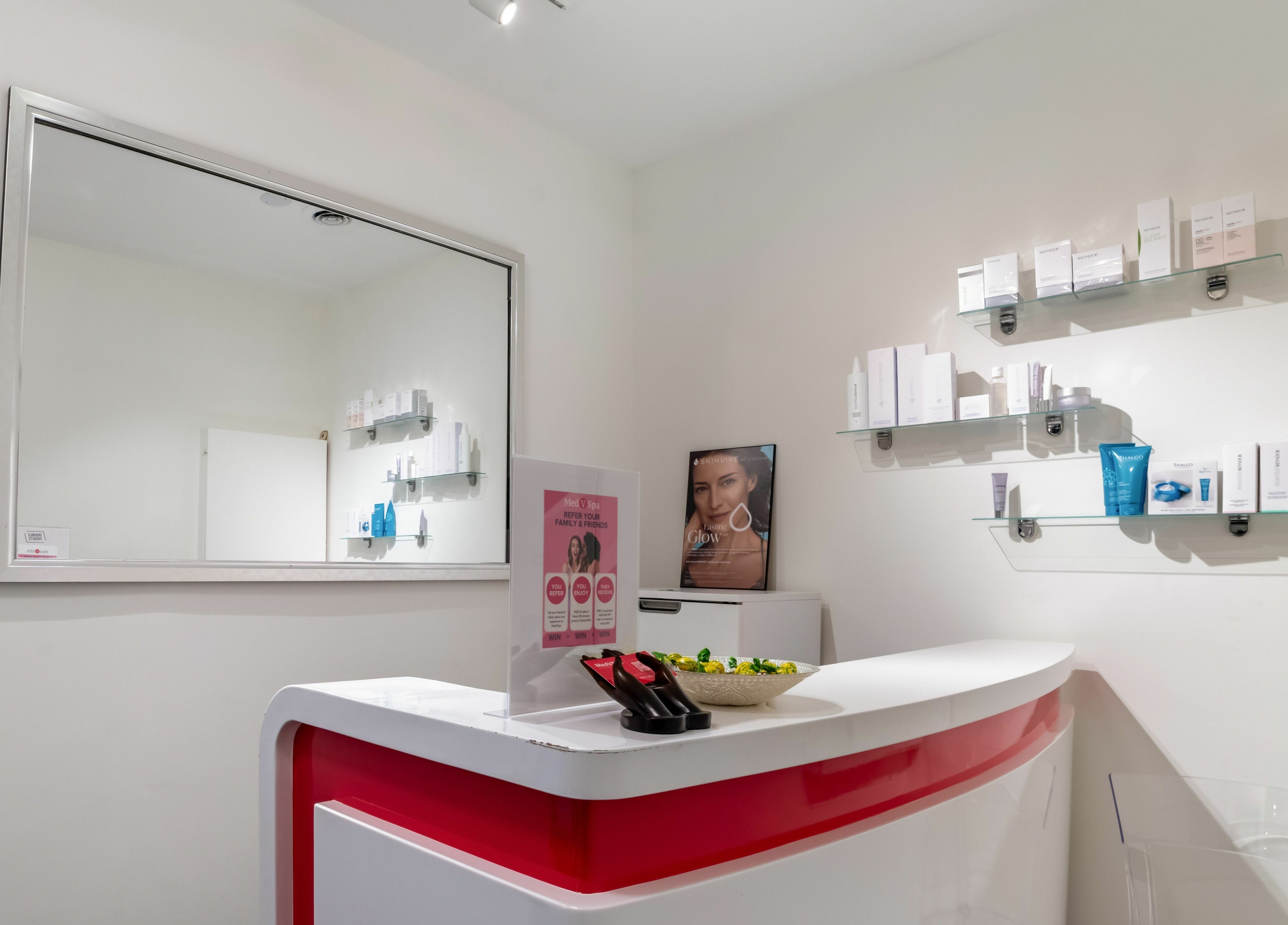 Reception area at MedVSpa in Toronto, Ontario, CA, featuring a modern white and red counter with beauty products.