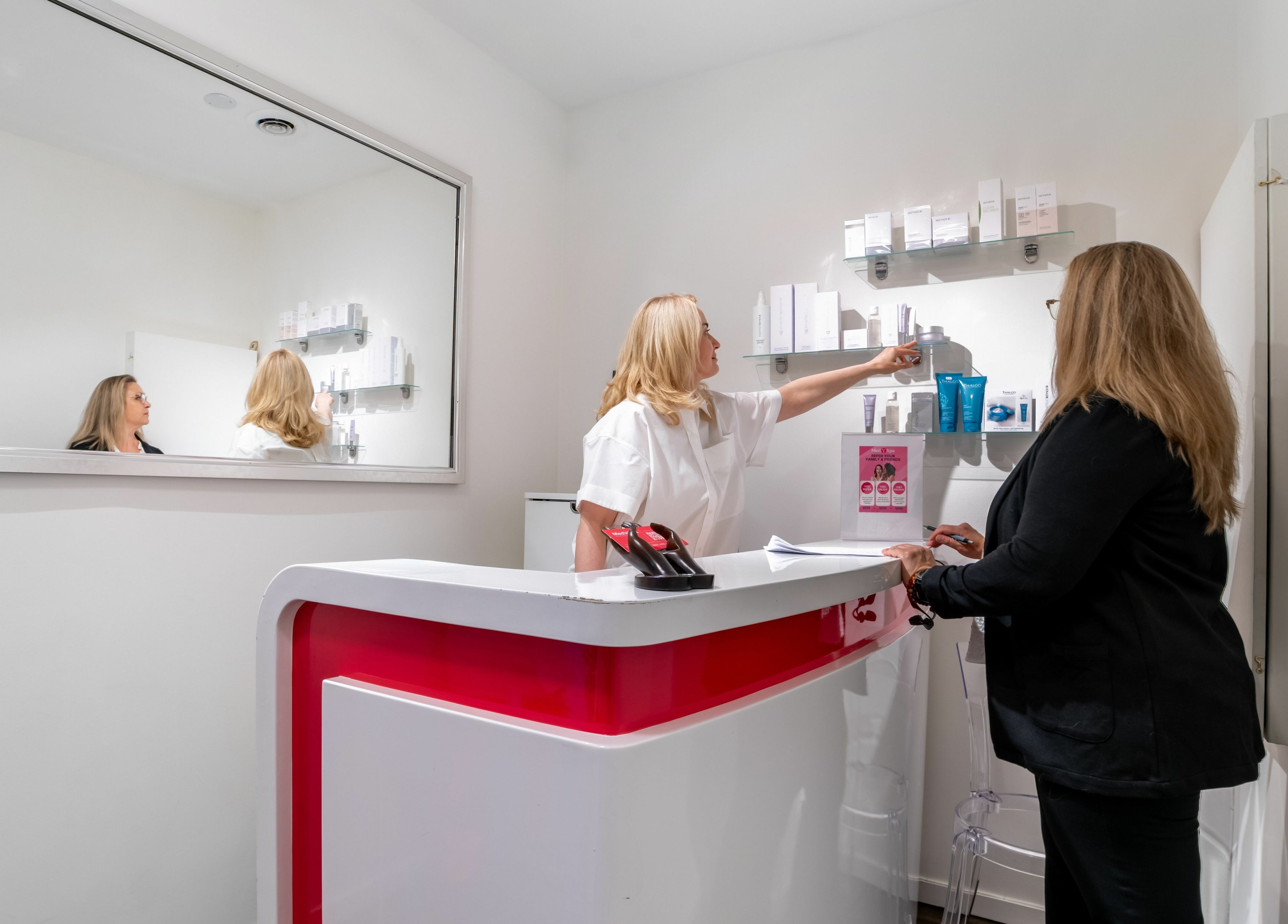 MedVSpa reception in Toronto, Ontario, CA with staff assisting a client behind a modern white desk.