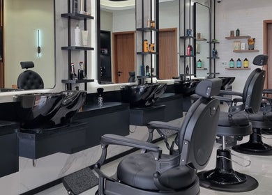 Elegant interior of Pitstop Barbers in Dubai, AE, featuring modern black chairs and mirrors.