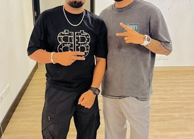 Two stylish men inside Pitstop Barbers, Dubai, AE, posing with peace signs.