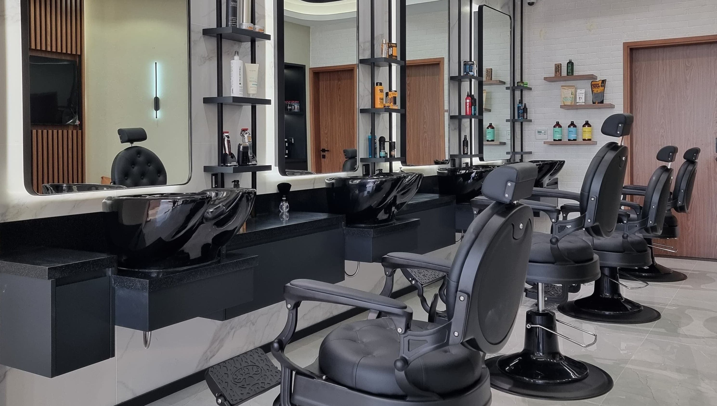 Modern barbershop interior at Pitstop Barbers in Dubai, AE, featuring sleek black chairs and wash stations.