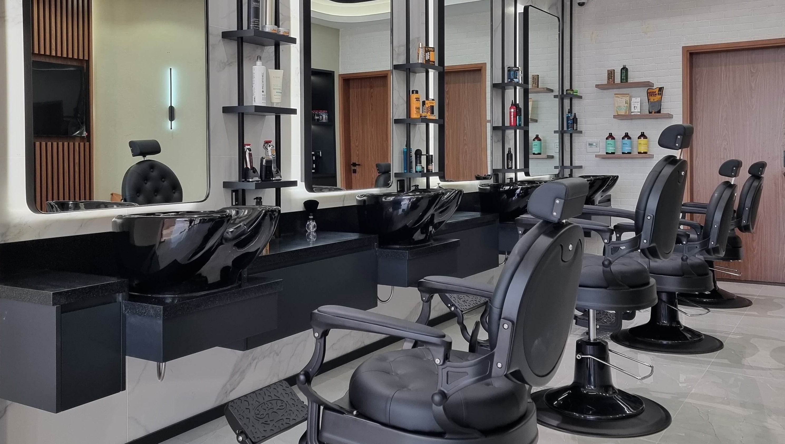 Modern barbershop interior at Pitstop Barbers in Dubai, AE, featuring sleek black chairs and wash stations.