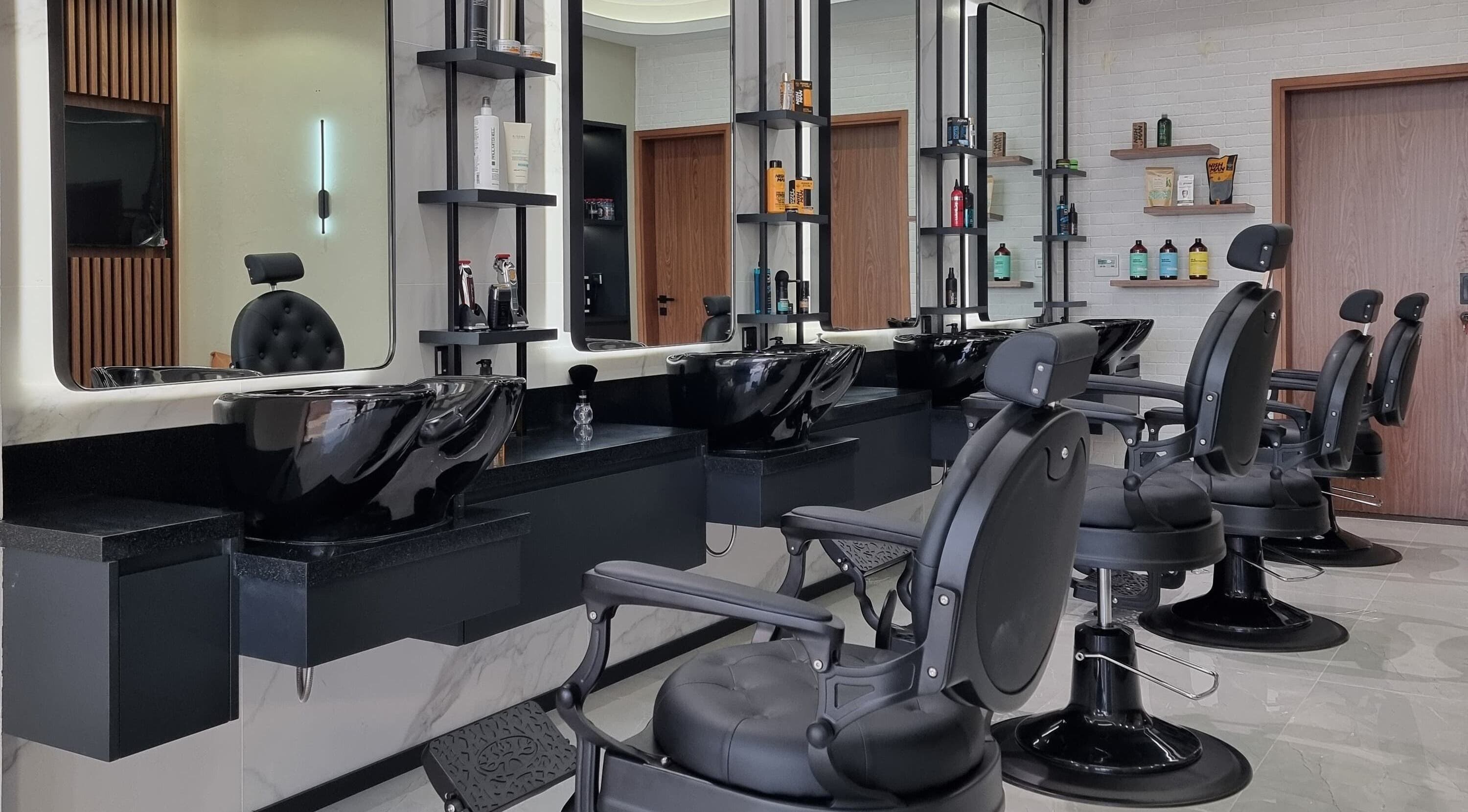 Modern barbershop interior at Pitstop Barbers in Dubai, AE, featuring sleek black chairs and wash stations.
