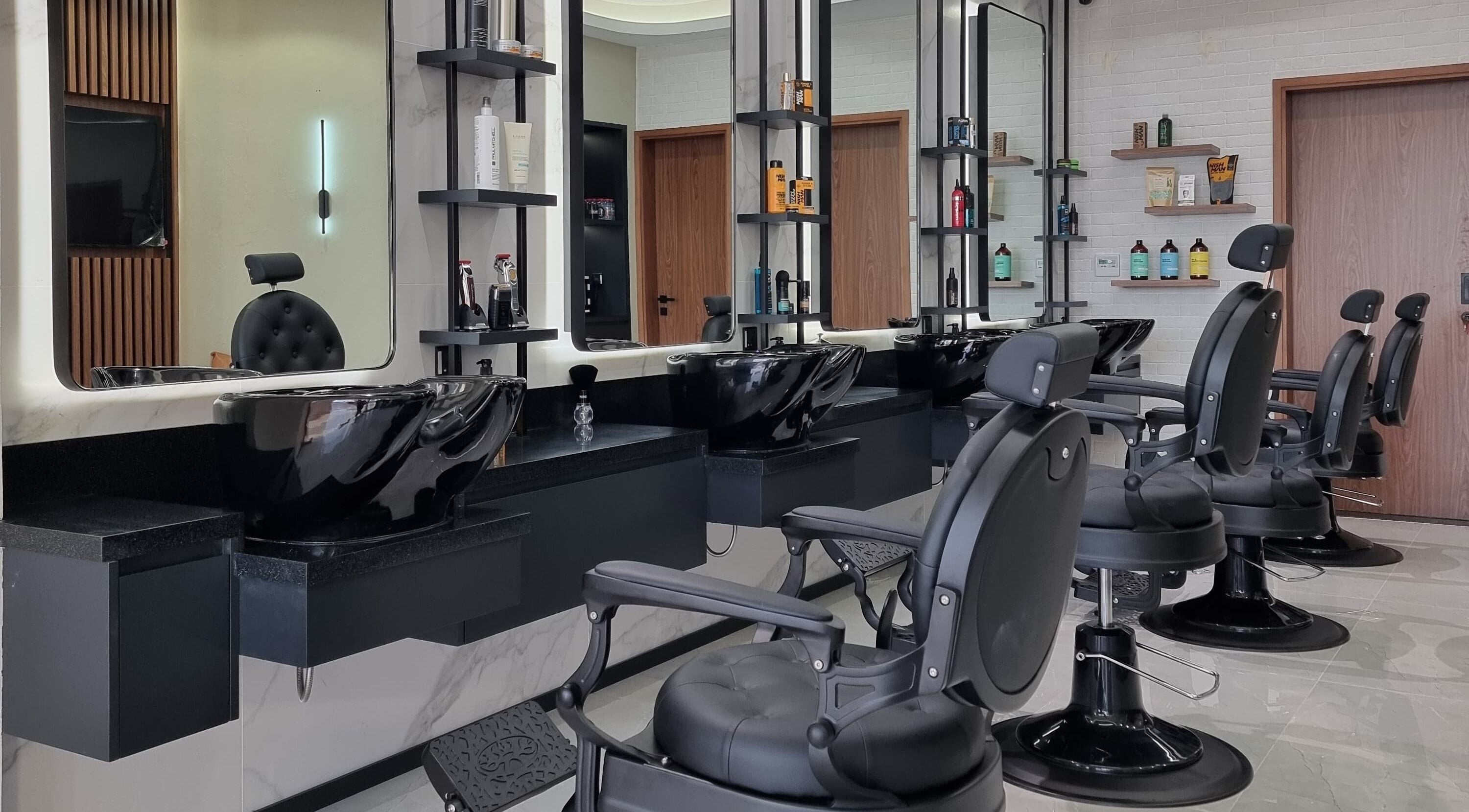 Modern barbershop interior at Pitstop Barbers in Dubai, AE, featuring sleek black chairs and wash stations.