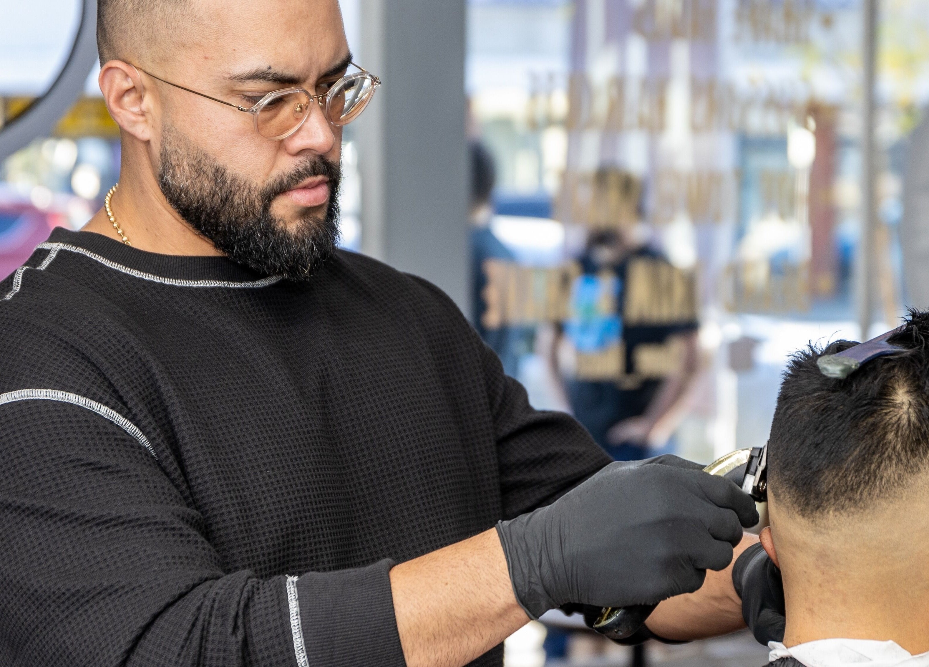 Barber styling client's hair at HC Shave House, Burbank, California, US. Precision haircut in natural light.