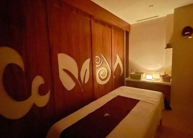 Sala de masajes en Quinto Elemento Spa - Tulum, Quintana Roo, MX, con luz tenue y arte en madera.