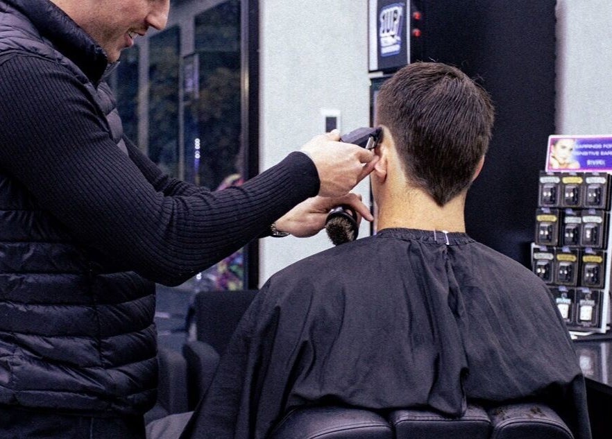Barber at 1UP Barbershop Bicton, Bicton, Western Australia, AU, expertly trims customer's hair.