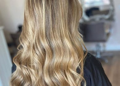 Golden wavy hairstyle at Gina Marks Hair in Elmswell, England, GB. Luxurious salon interior in background.