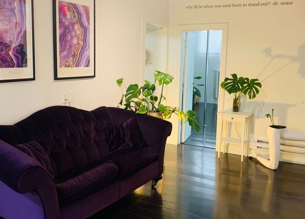 Elegant spa lounge at CoalitionSkin | Holistic Spa Downtown Vancouver, featuring purple sofa and art, Vancouver, BC, CA.