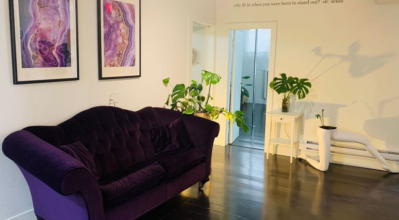 Elegant spa lounge at CoalitionSkin | Holistic Spa Downtown Vancouver, featuring purple sofa and art, Vancouver, BC, CA.