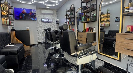Interior moderno de Monarca Barberia - Miraflores en LIMA, Provincia De Lima, PE con sillas negras y espejo iluminado.