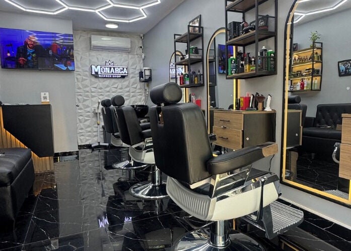 Interior moderno de Monarca Barberia - Miraflores en LIMA, Provincia De Lima, PE, mostrando sillas y espejos elegantes.