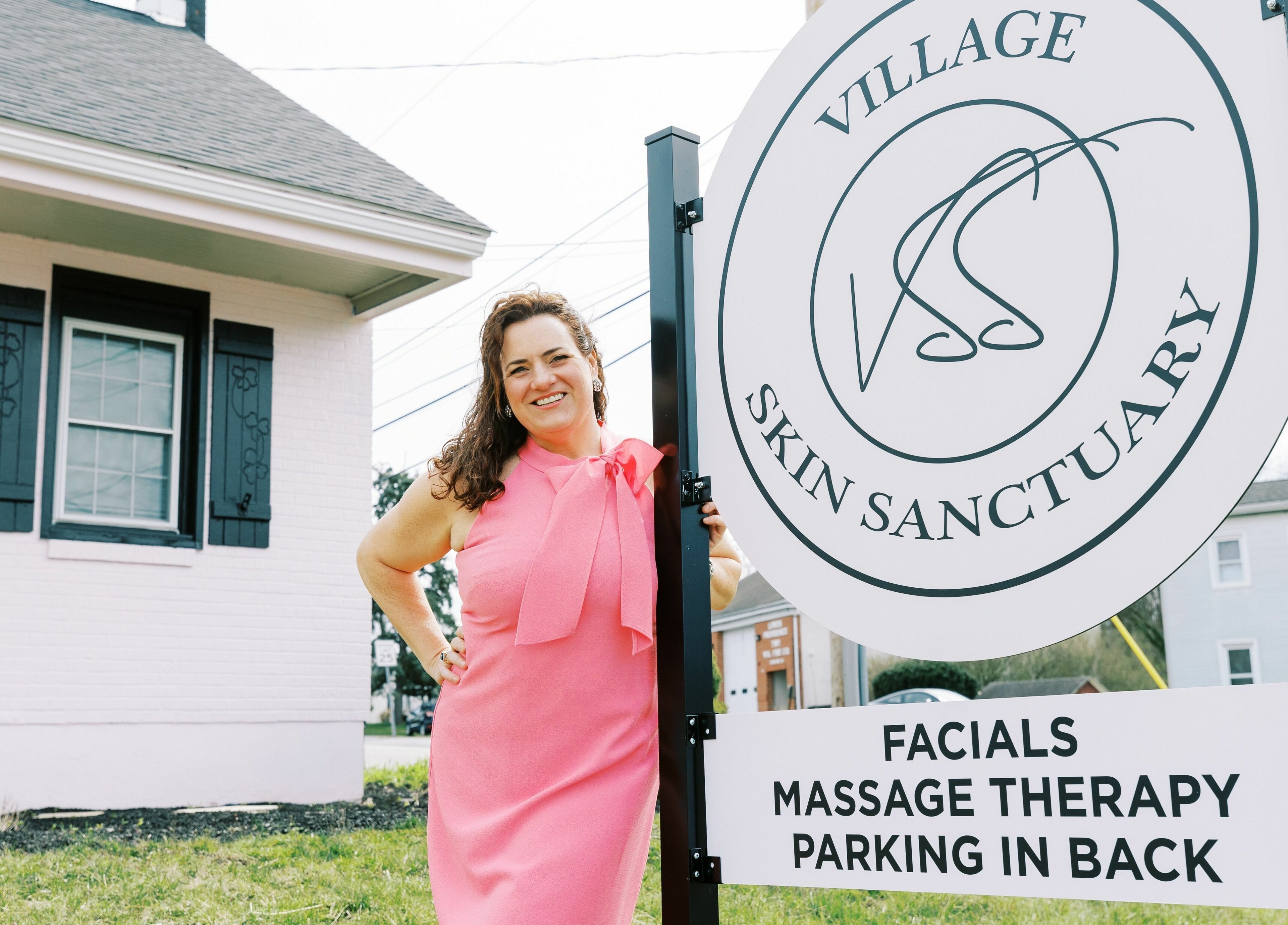 Woman in pink dress by Village Skin Sanctuary sign, Audubon, Pennsylvania, US.