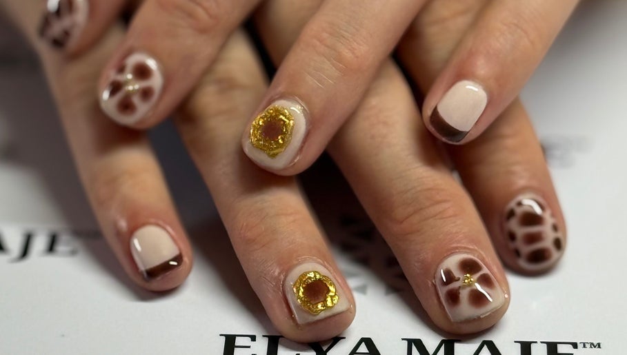 Nail art élégant à Nailstrauss, Epagny, Hauts-de-France, FR, avec motifs dorés et bruns.
