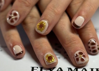 Nail art élégant à Nailstrauss, Epagny, Hauts-de-France, FR, avec motifs dorés et bruns.